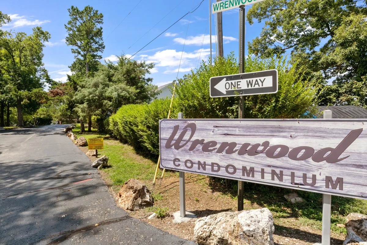 This image shows the welcoming entrance to the Wrenwood Condominium community, with its prominent sign, lush surrounding greenery, and a road leading into the property. The scene exudes an inviting community atmosphere, ideal for first-time guests and their pets.