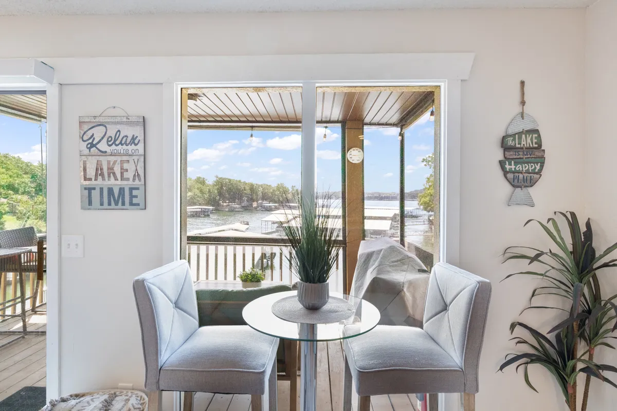 This interior shows a dining table set by large windows with an impressive lake view, complemented by decorative touches like signs. The tranquil ambiance is ideal for quiet meals, drinks, or simply gazing at the changing light over the water.