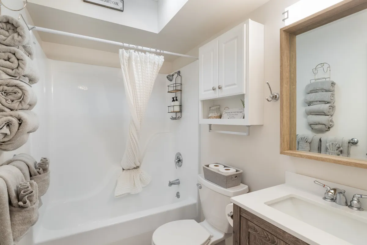 An ensuite bathroom featuring a luxurious soaking bathtub, modern sink, convenient towel storage, and a well-lit mirror. Fluffy towels and elegant finishes convey a spa-like experience.
