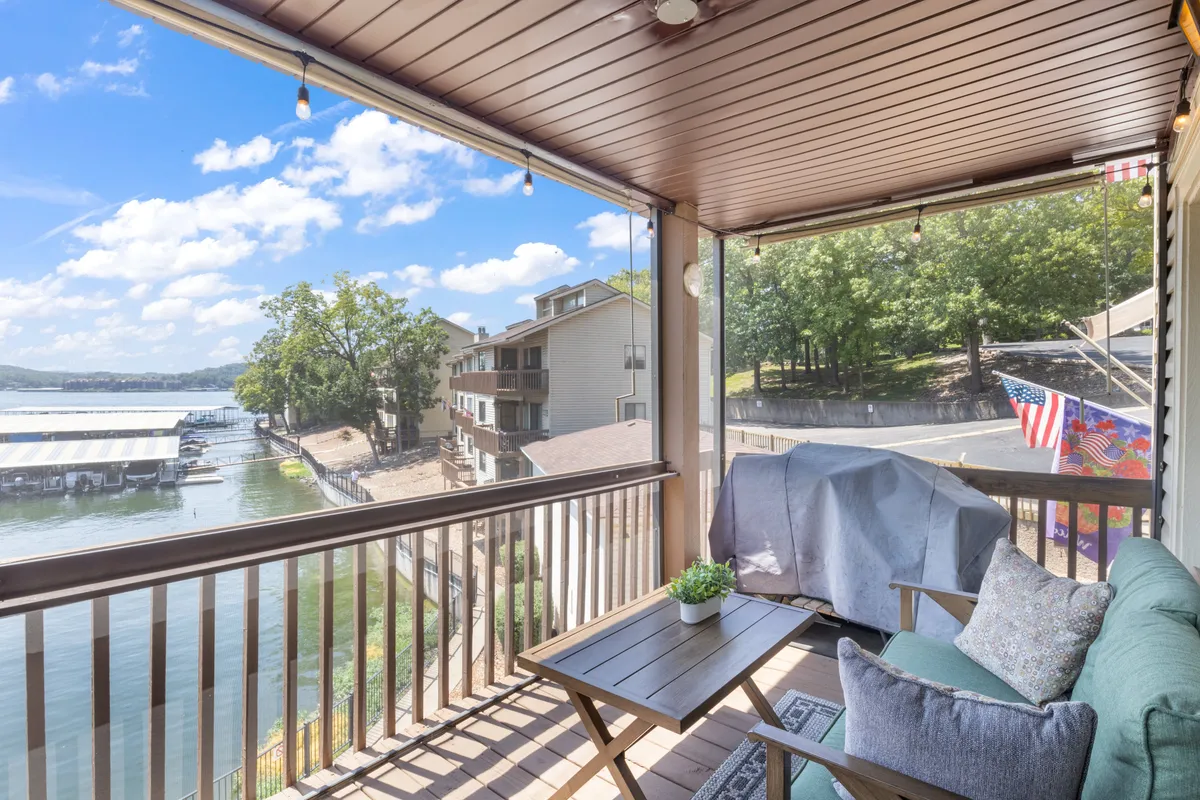 An outdoor seating area with comfortable chairs, a decorative plant, and an American flag, all set against a serene water view. The space invites relaxation, sunrise coffee, or sunset gatherings by the lakeside.